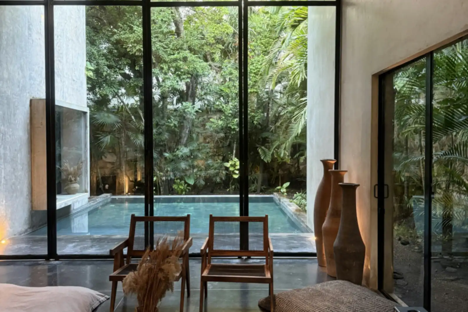Villa 2 phòng ngủ ở Côn Đảo: phòng khách thông tầng, ghế gỗ thấp và cửa kính mở ra hồ bơi