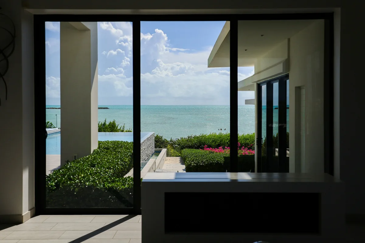 Khung cửa kính lớn của villa nhìn ra vườn và biển